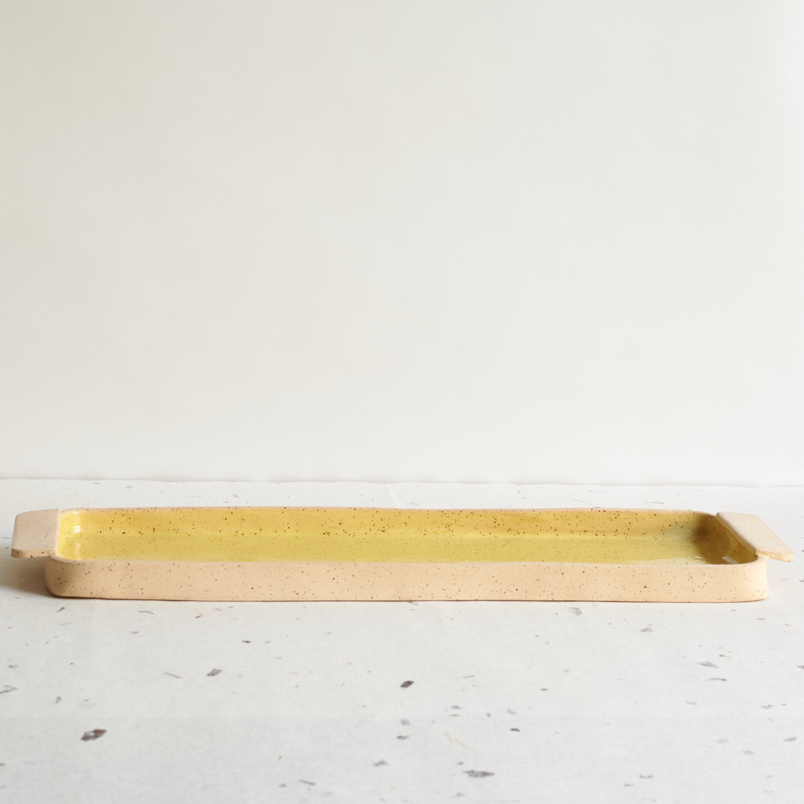 Yellow rectangular serving platter made of speckled stoneware