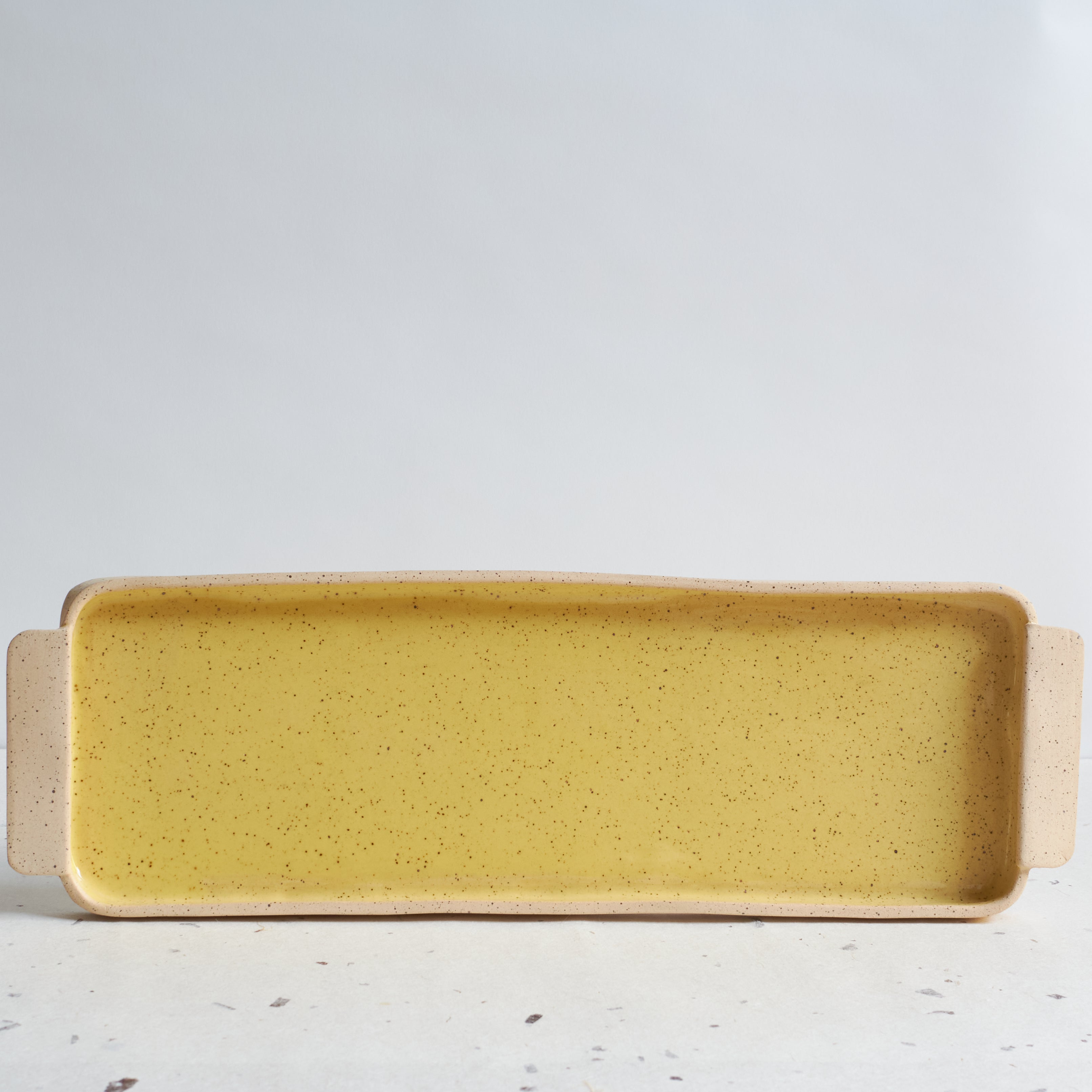 Yellow rectangular serving platter made of speckled stoneware
