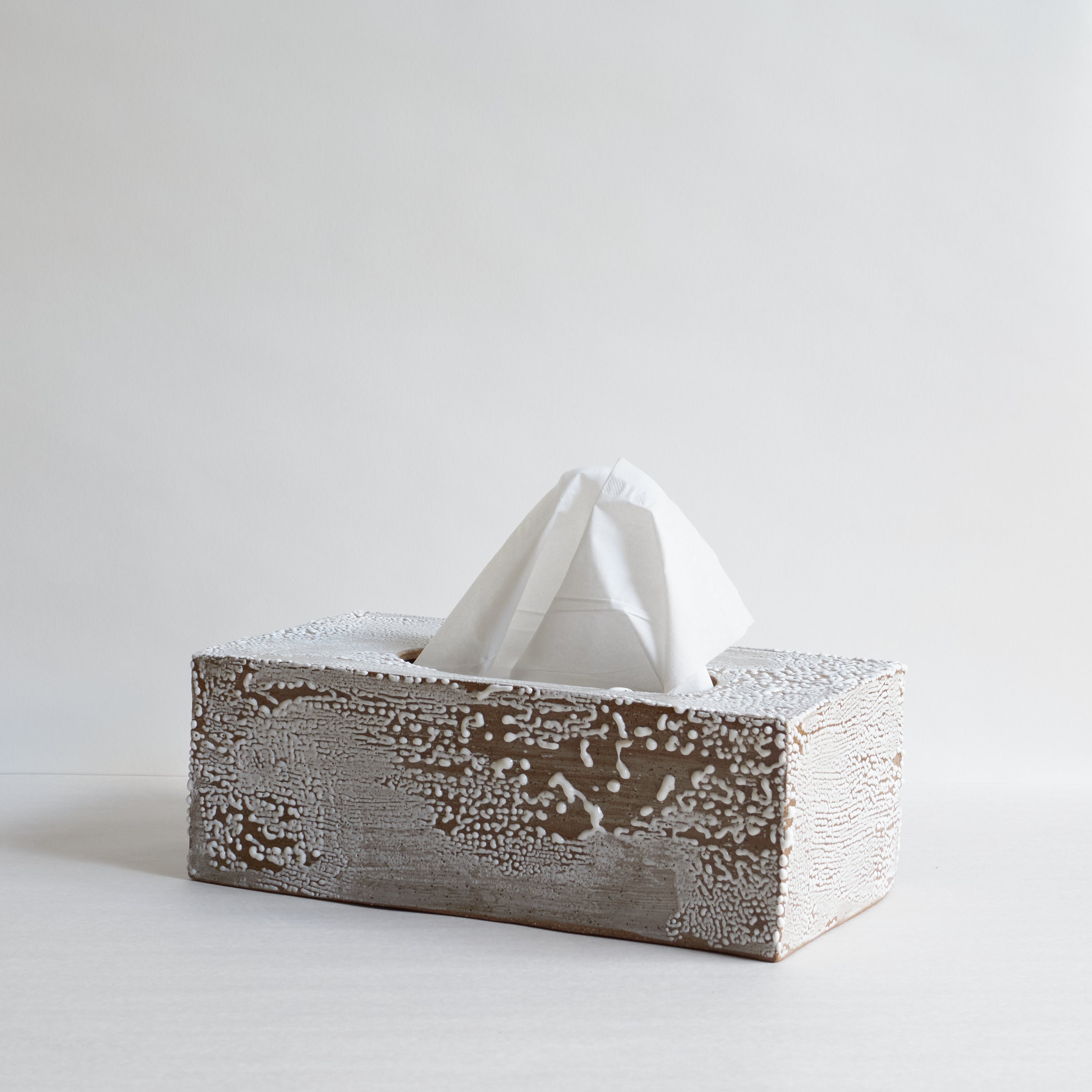 Ceramic tissue box with white tissues on a light gray background