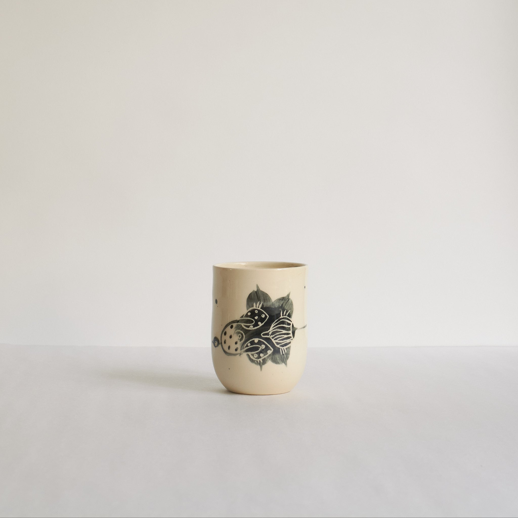 Black and white earthenware tumbler with carved patterns on a light background