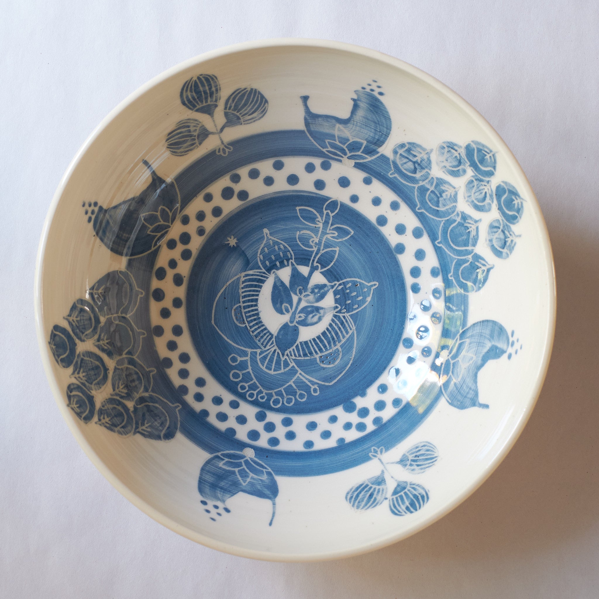 Blue handmade ceramic serving bowl with blue and black decorative carved patterns on a white background