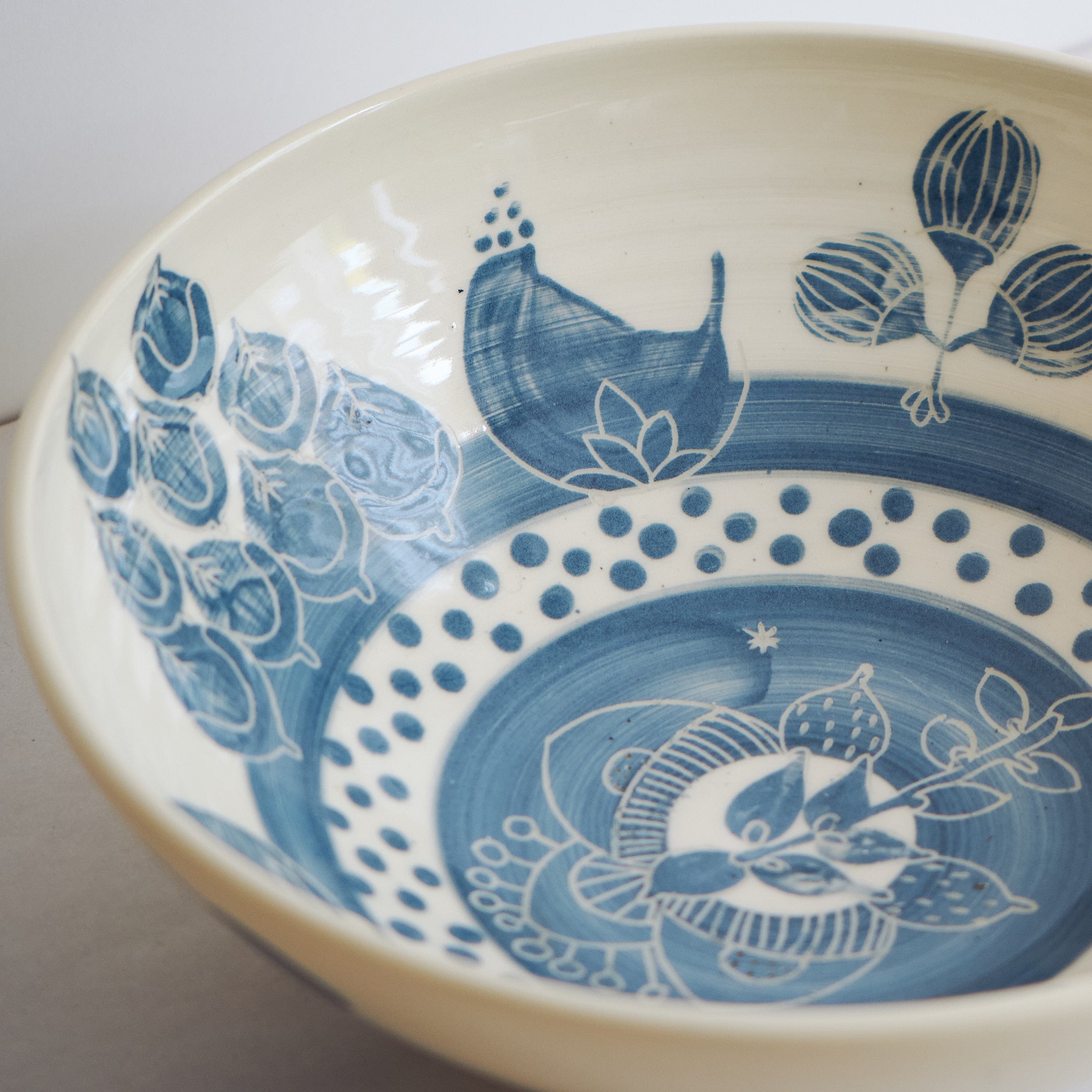 Blue handmade ceramic serving bowl with blue and black decorative carved patterns on a white background