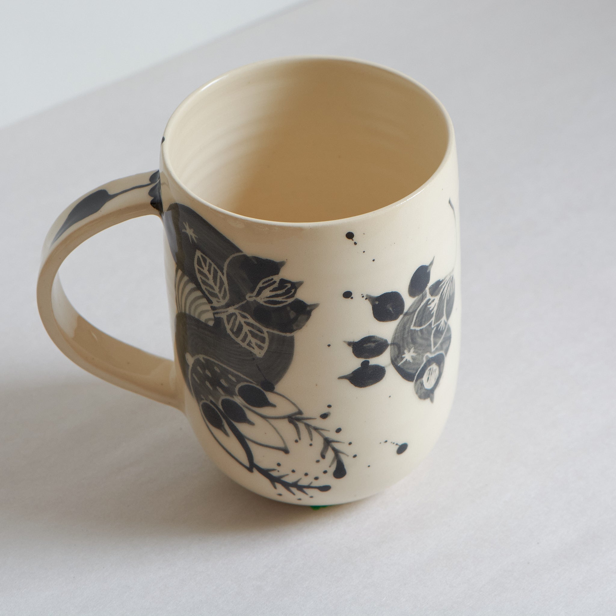 Tall white earthenware mug with black carvings