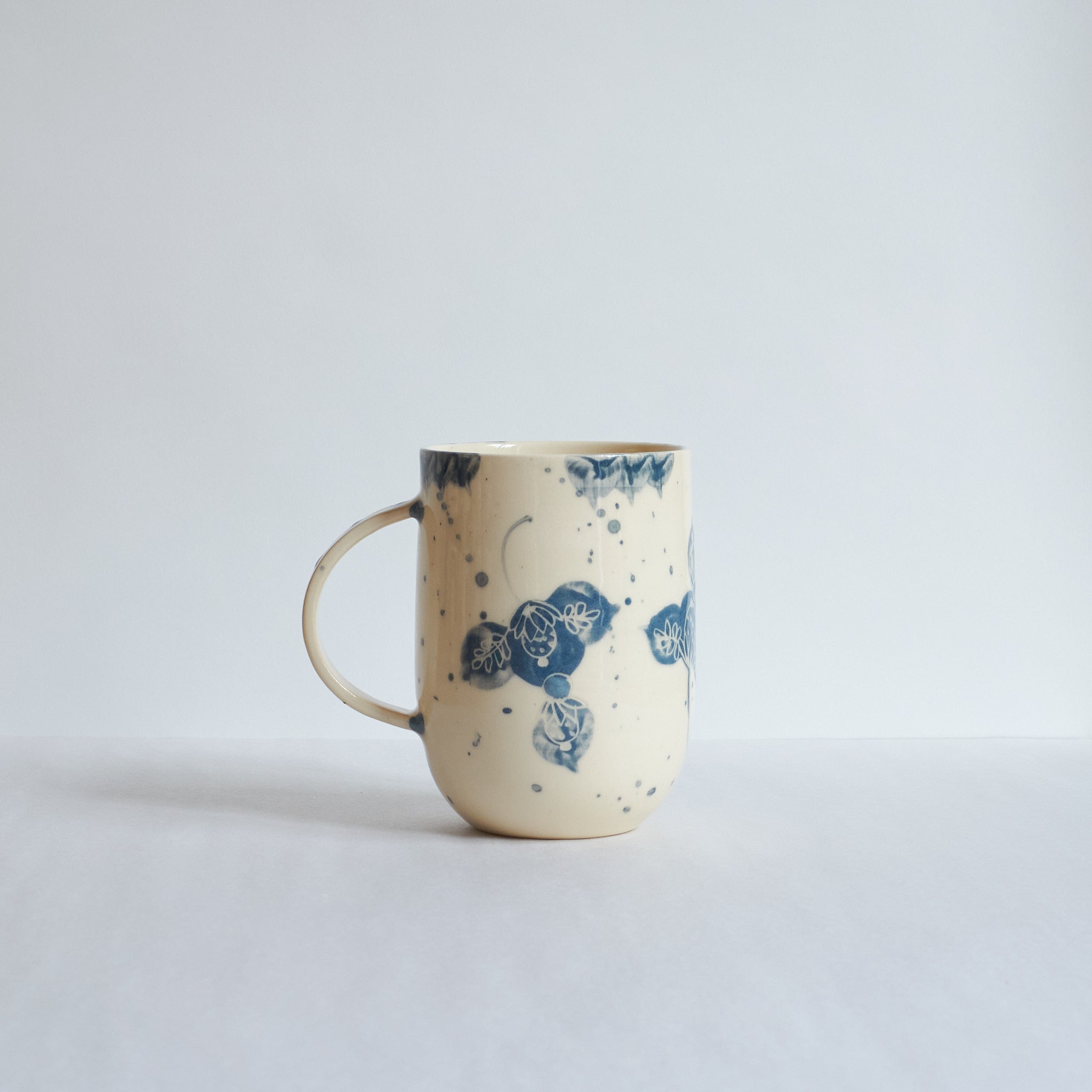 Tall white earthenware mug with blue carvings