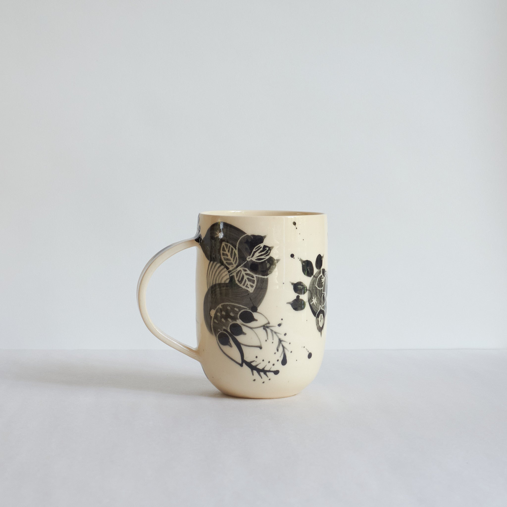 Tall white earthenware mug with black carvings