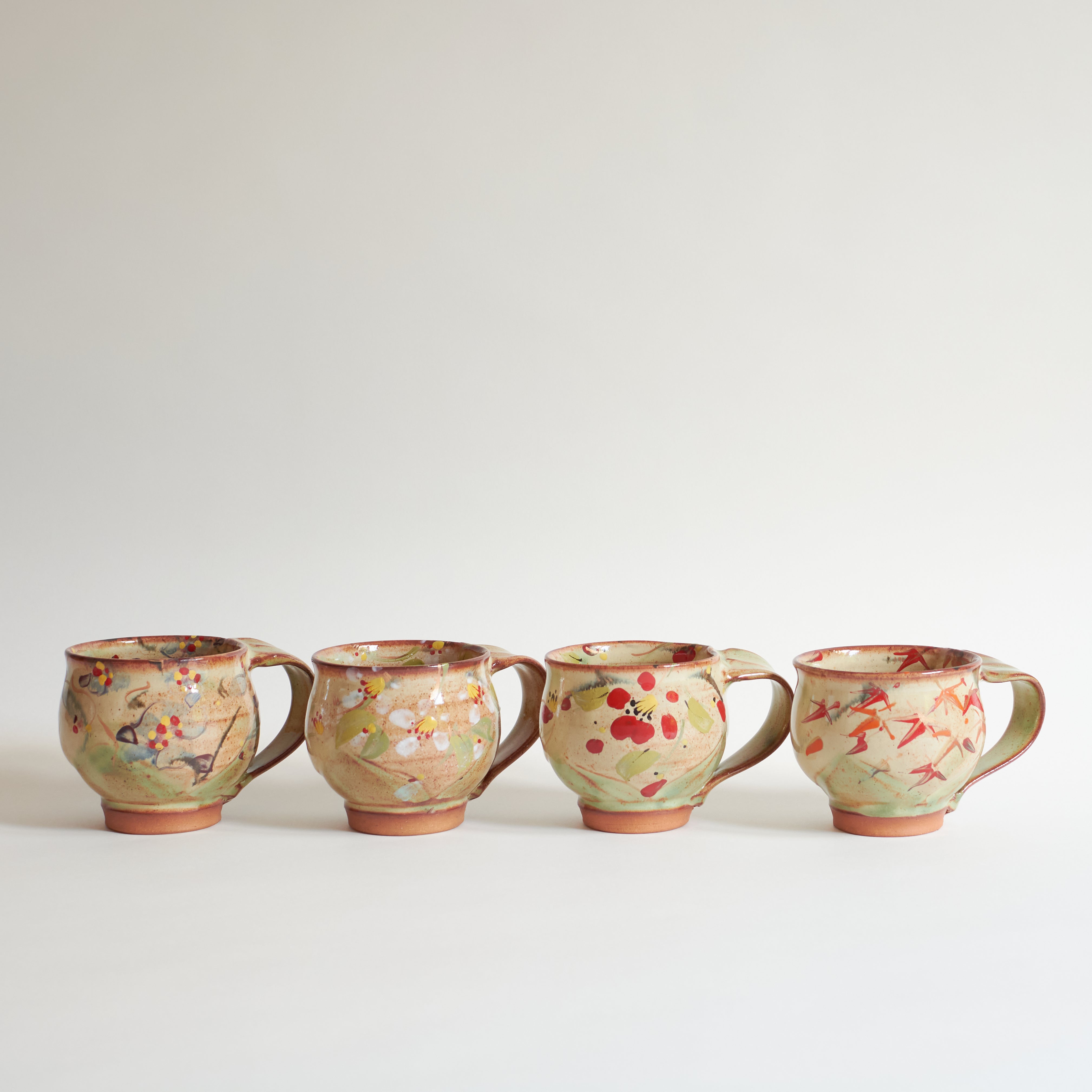 Four ceramic mugs with floral patterns on a white background