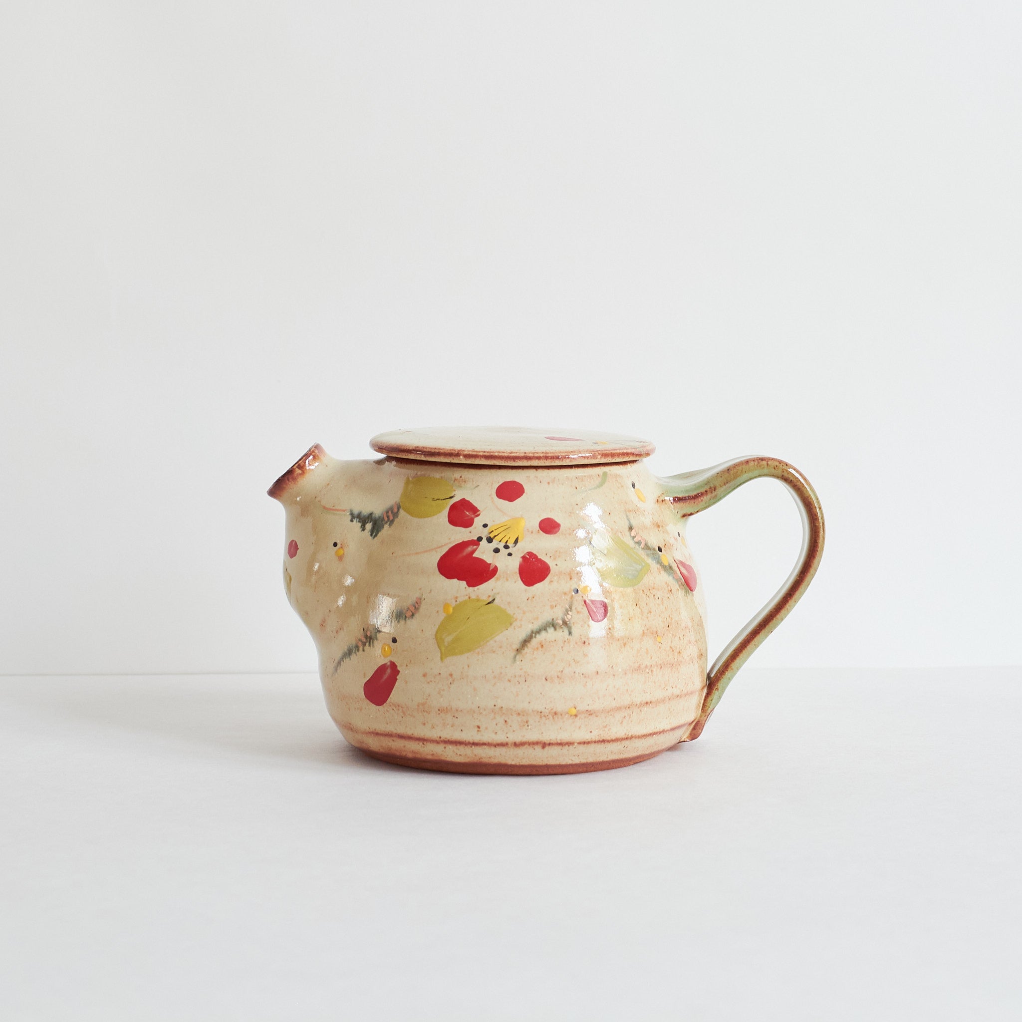 Ceramic teapot with winter red camellia design on a white background