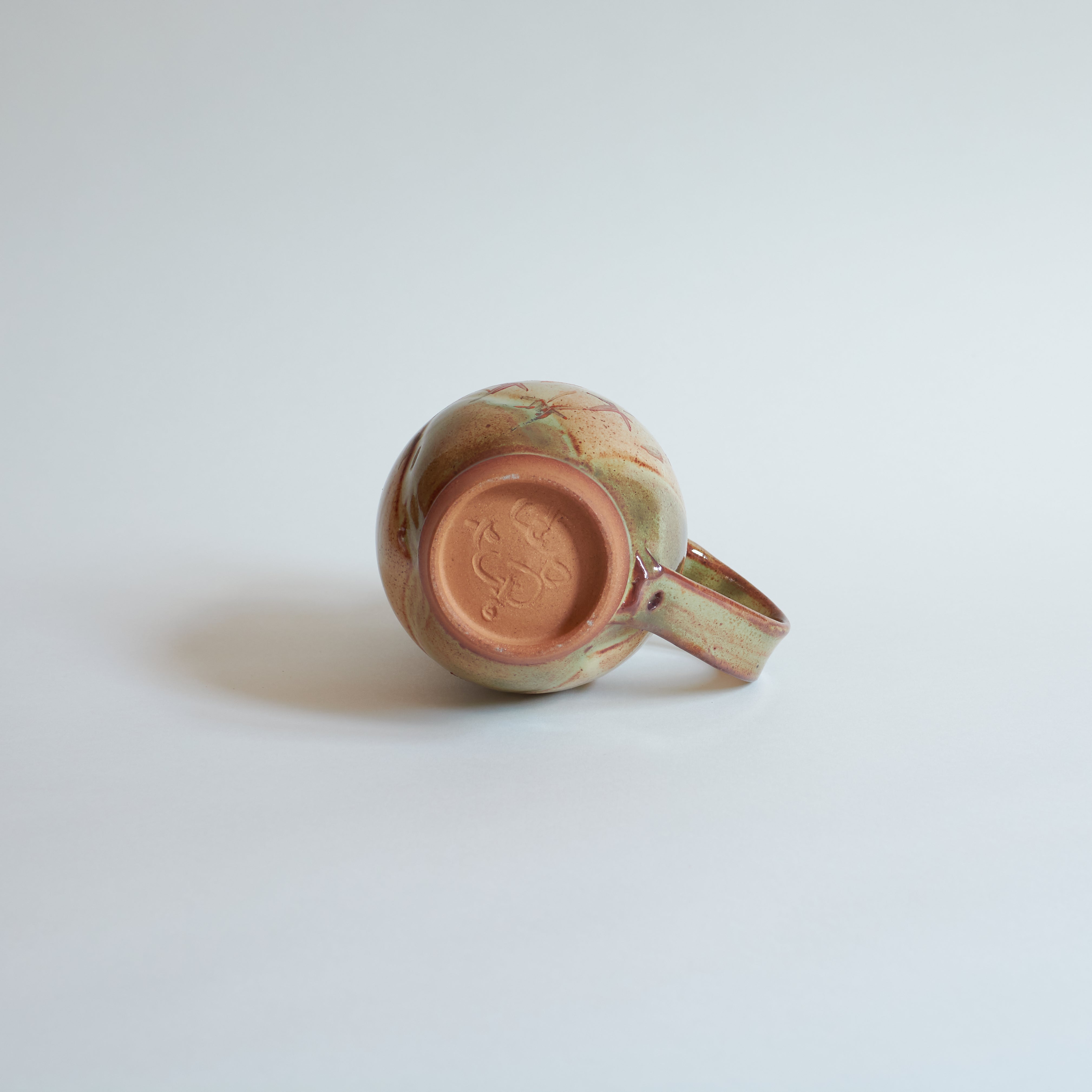 Bottom of ceramic mug on a light gray background.