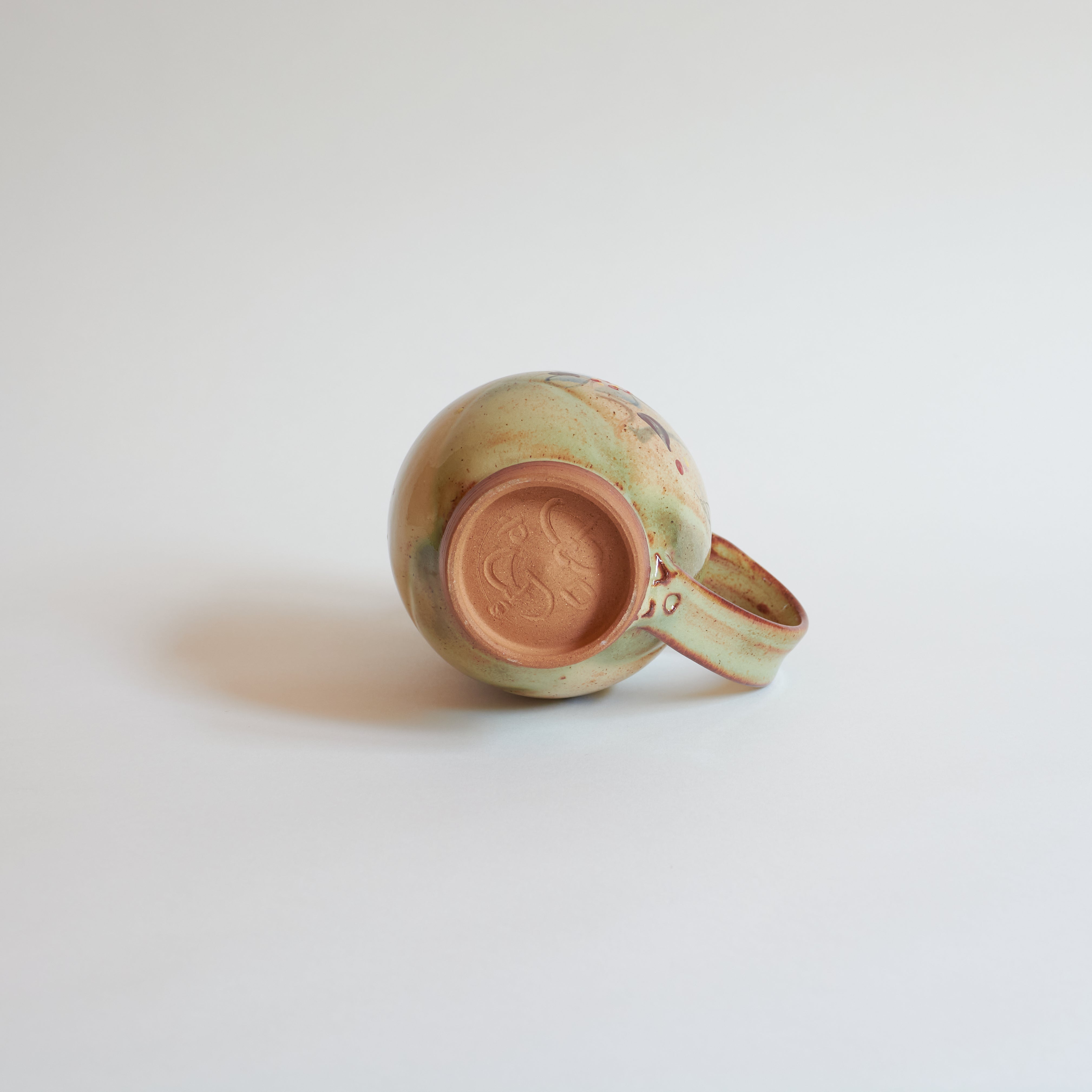 Bottom of ceramic mug on a light gray background.