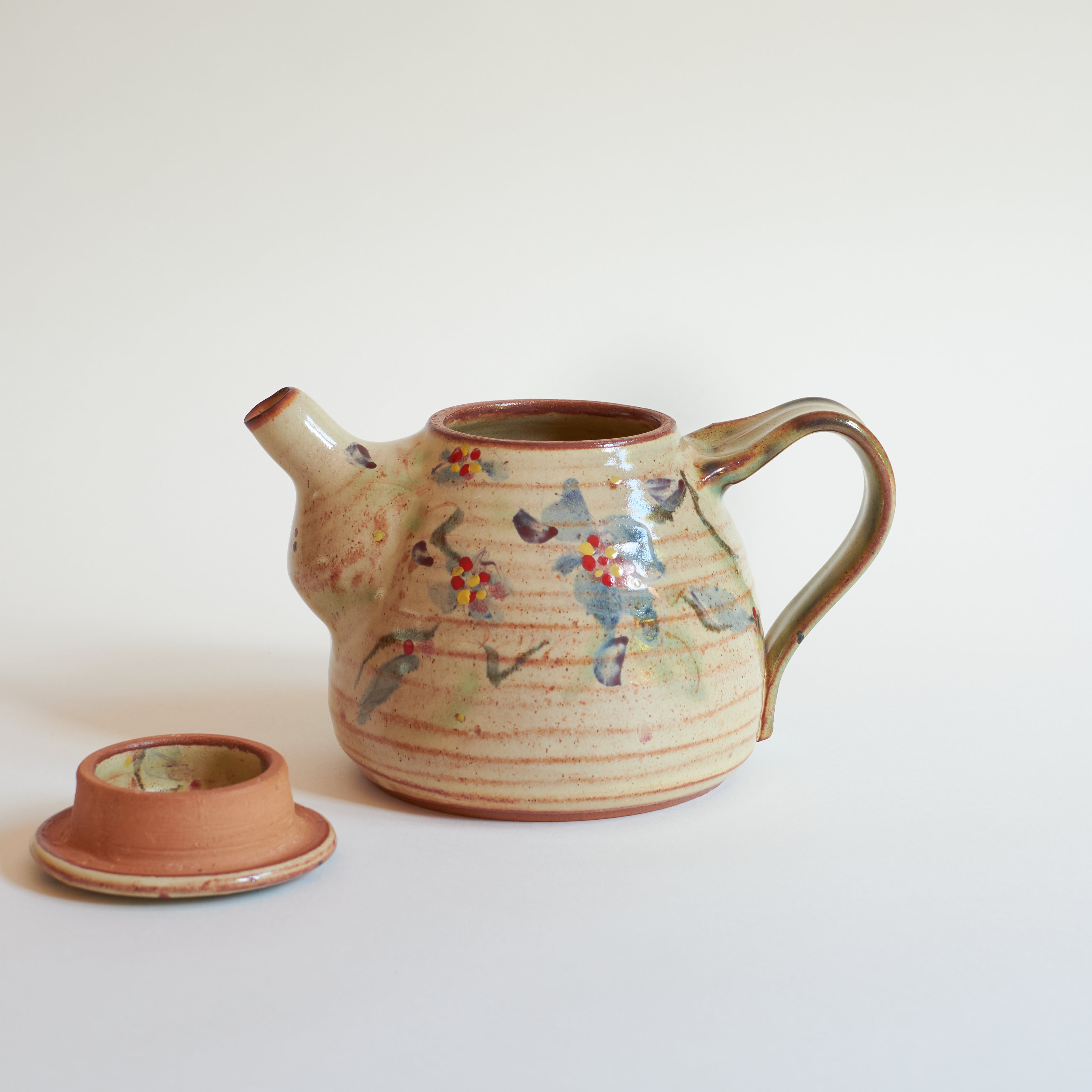 Ceramic teapot with floral designs on a white background
