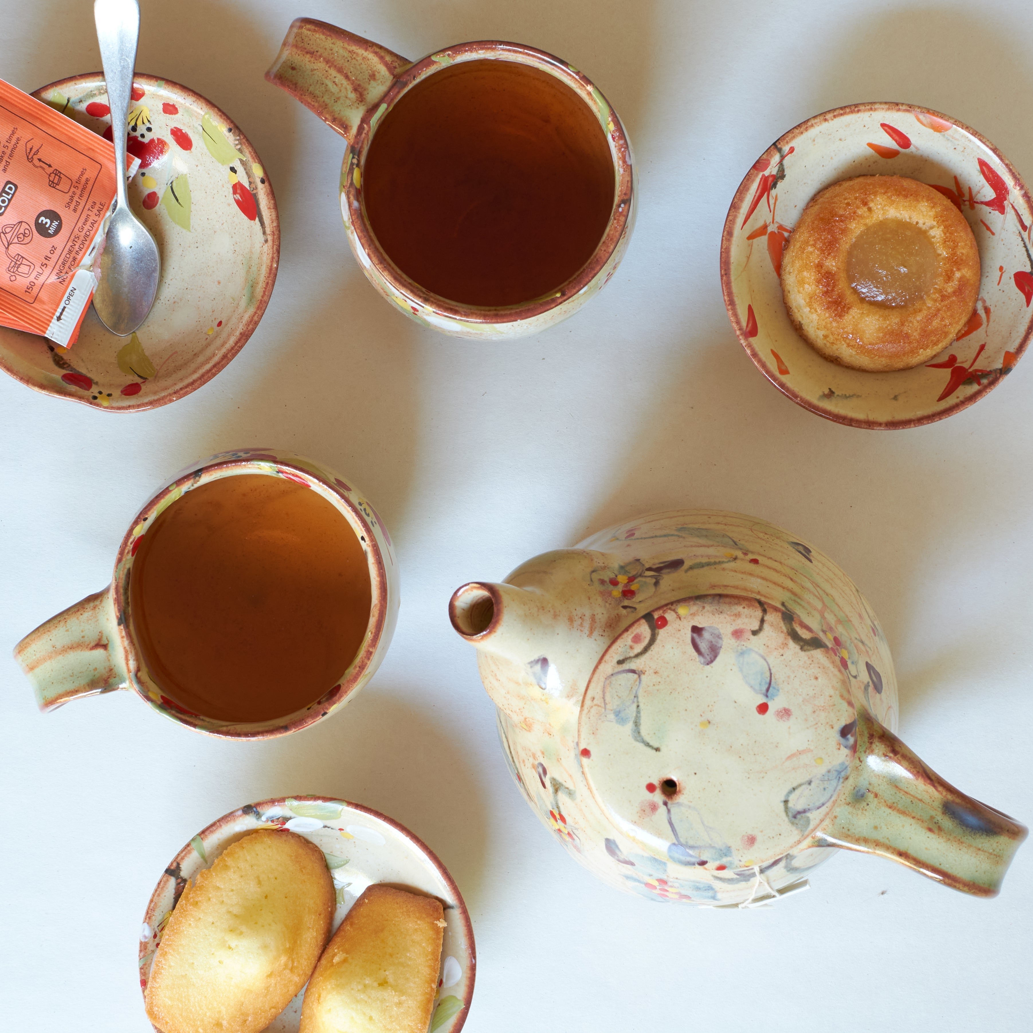 Japanese teapot with cups and small plate with financier and madeleines baked goods.