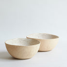 Two large off-white bowls made of speckled stoneware 