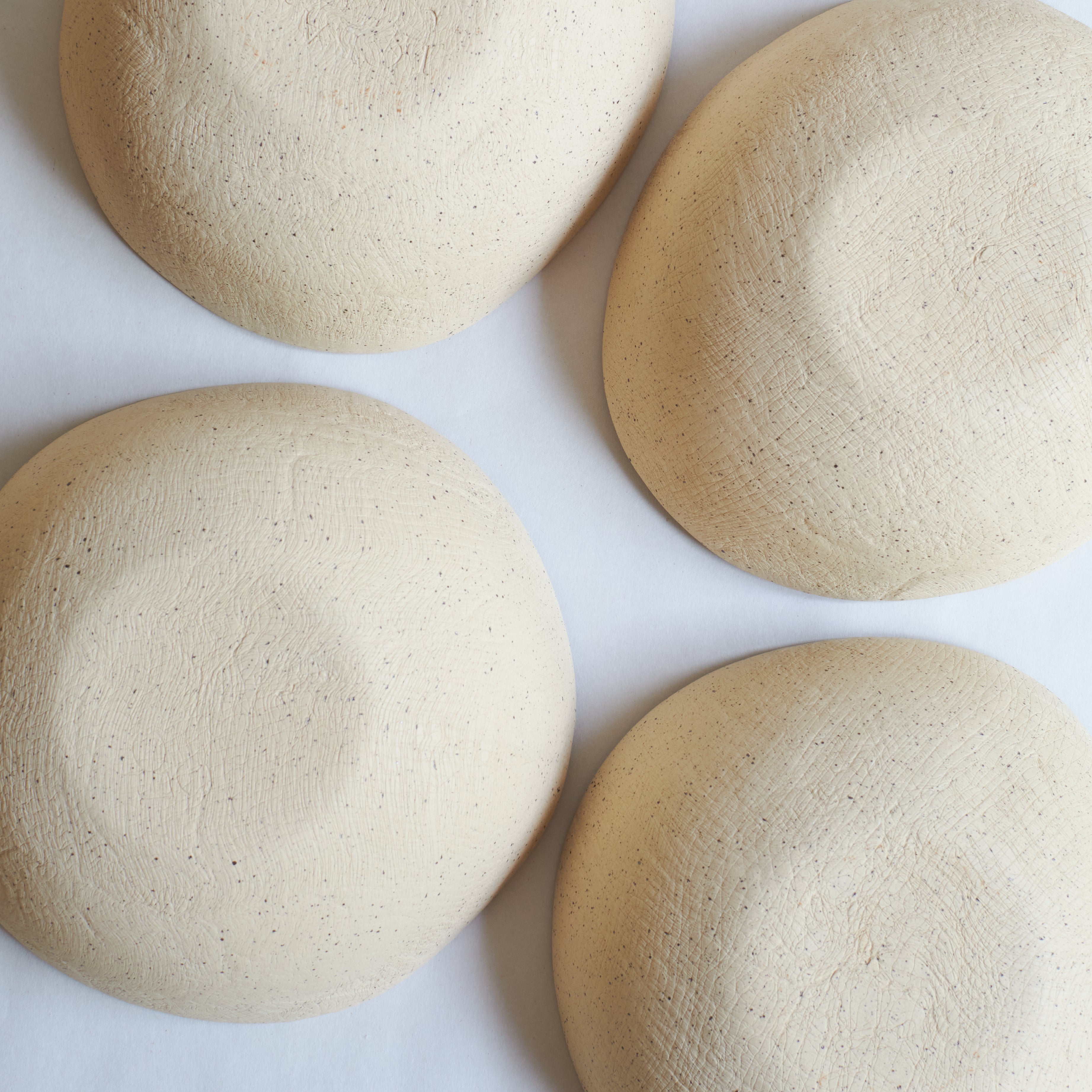 Bottom view of four large off-white bowls made of speckled stoneware 