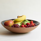 Fruit bowl with apples, bananas, grapes, and strawberries on a light background