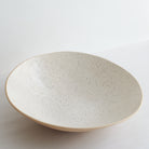 Speckled ceramic fruit bowl on a light gray background