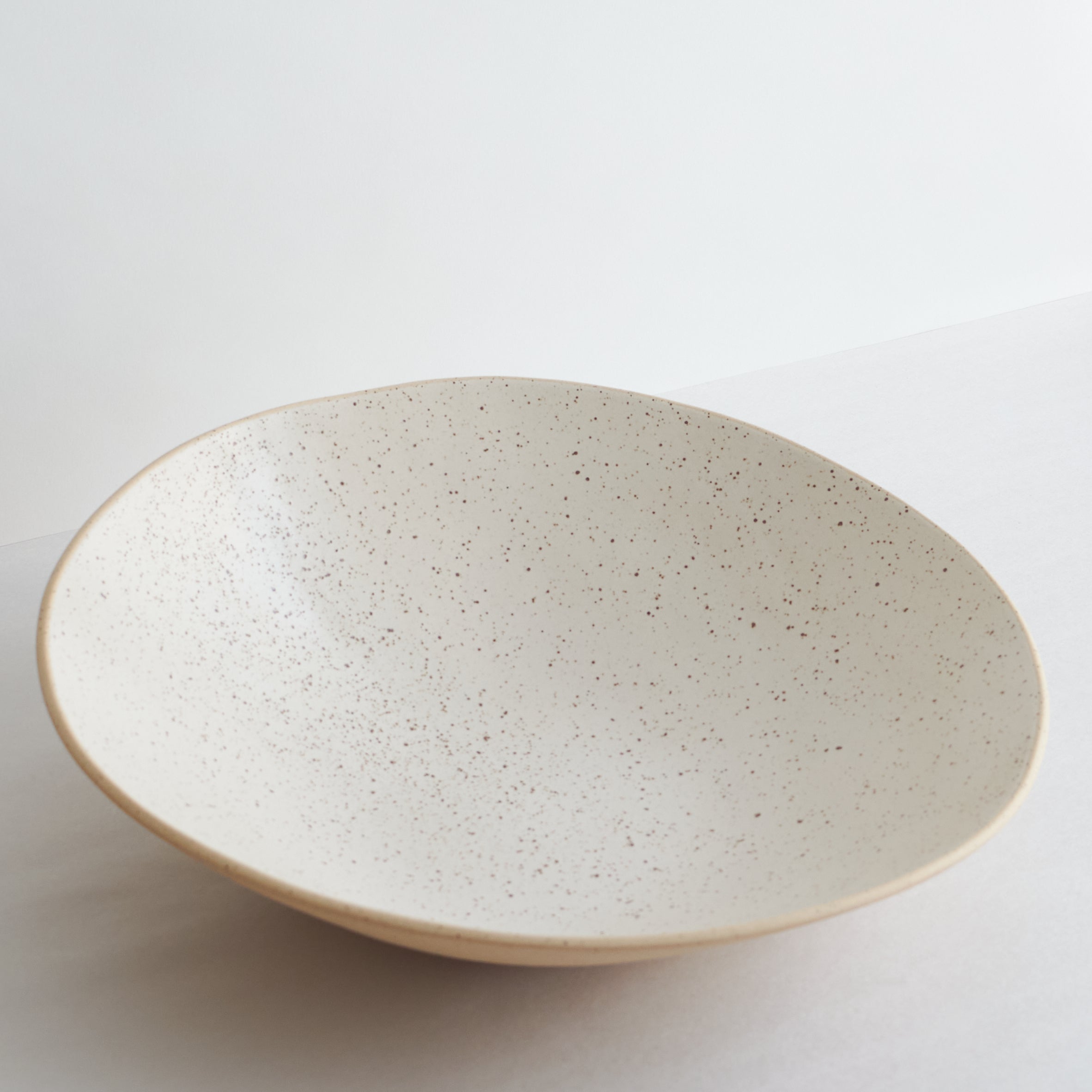 Speckled ceramic fruit bowl on a light gray background