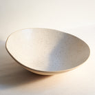 Speckled off-white ceramic fruit bowl on a light background