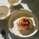 Speckled off-white ceramic plate with  apples on a tablecloth