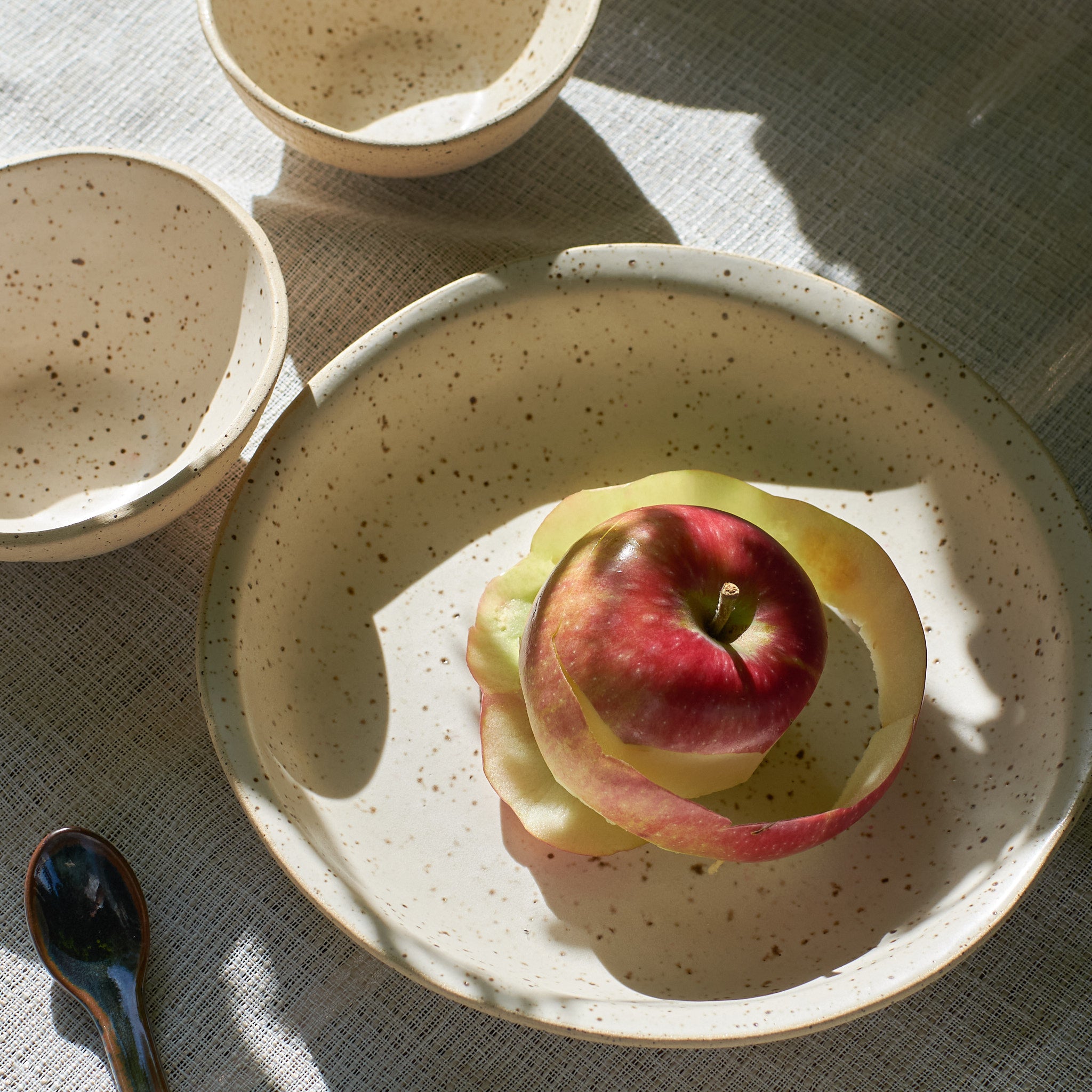 Speckled off-white ceramic plate with  apples on a tablecloth
