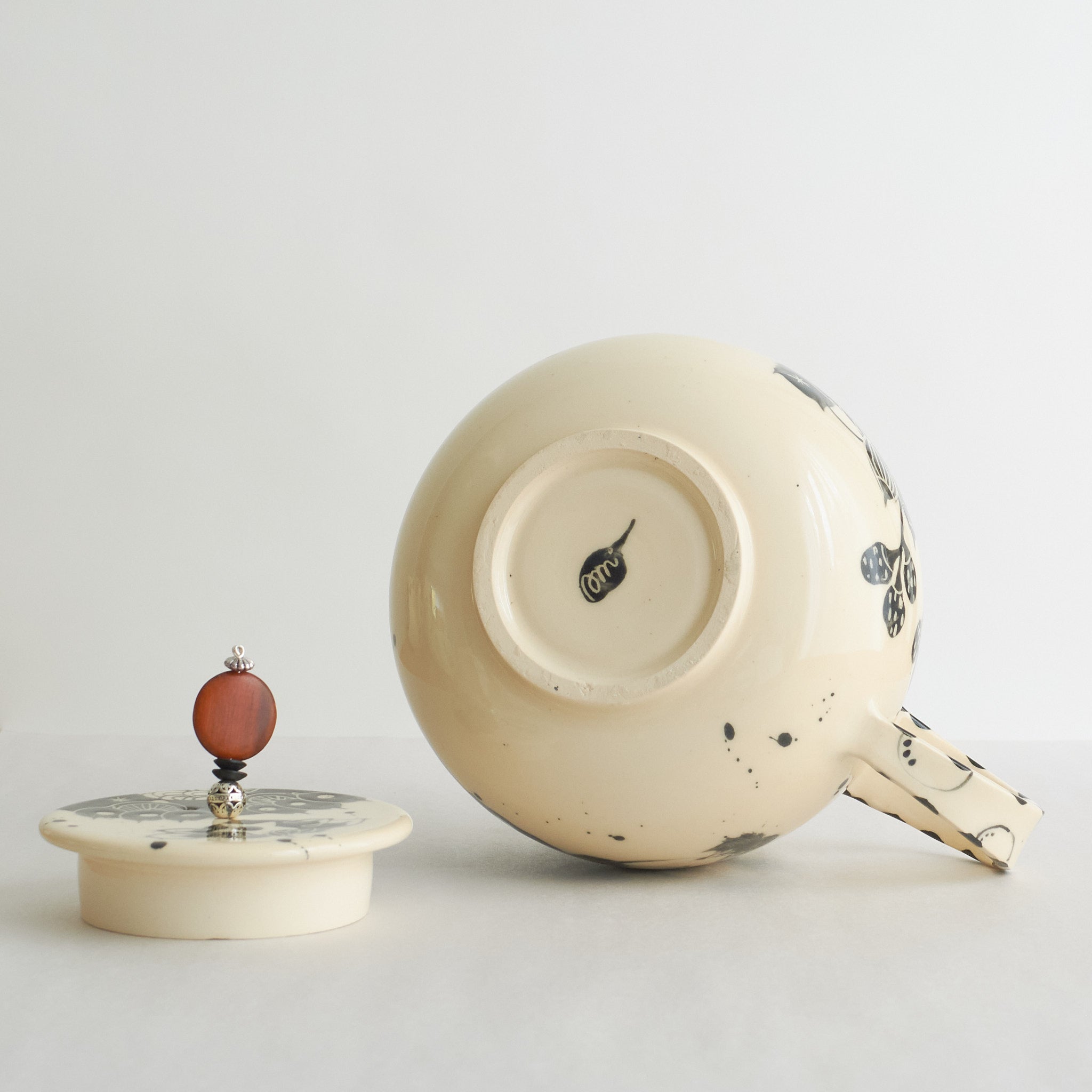 Black and white earthenware teapot with beaded pull on a white background