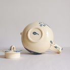 Bottom view of white earthenware teapot with blue carvings