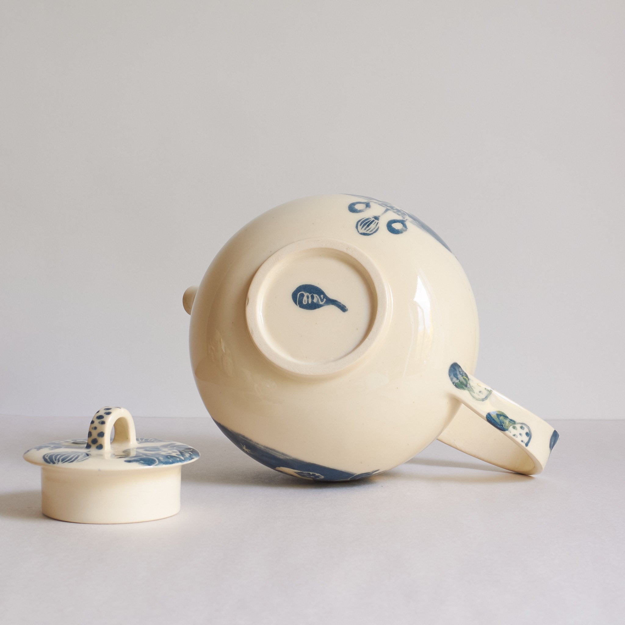 Bottom view of white earthenware teapot with blue carvings