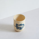 Side view of blue and white earthenware tumbler with carved patterns on a light background