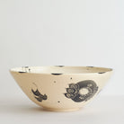 Black handmade ceramic serving bowl with blue and black decorative carved patterns on a white background