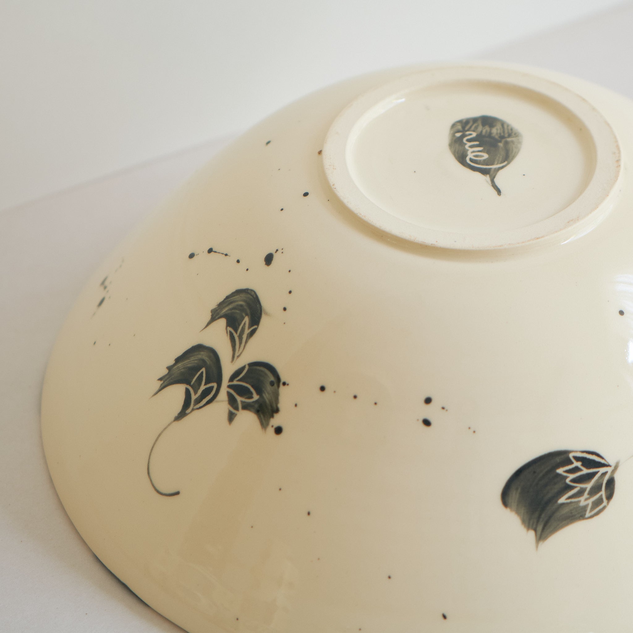 Bottom view of black handmade ceramic serving bowl with blue and black decorative carved patterns on a white background