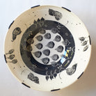 Black handmade ceramic serving bowl with blue and black with detailed decorative carved patterns on a white background
