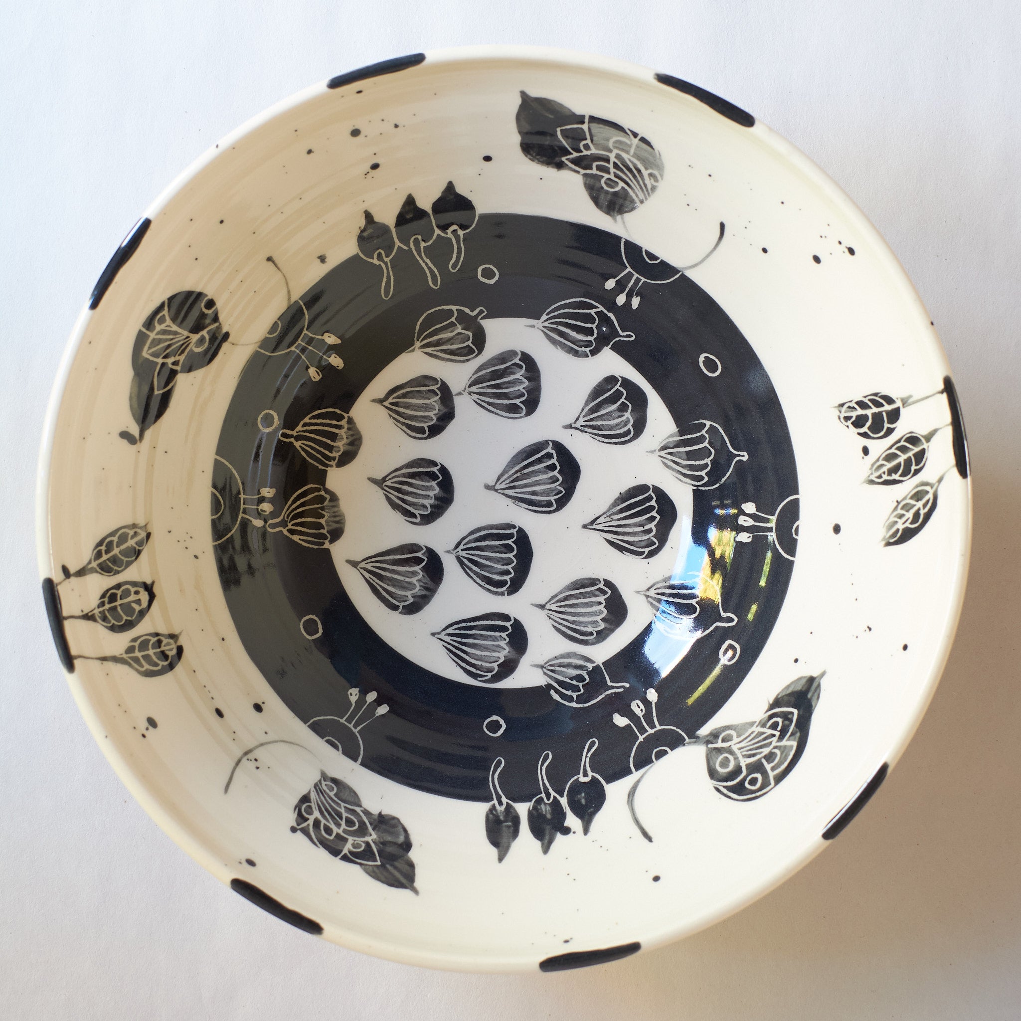 Black handmade ceramic serving bowl with blue and black with detailed decorative carved patterns on a white background