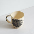 Small black and white earthenware cup with unique carvings