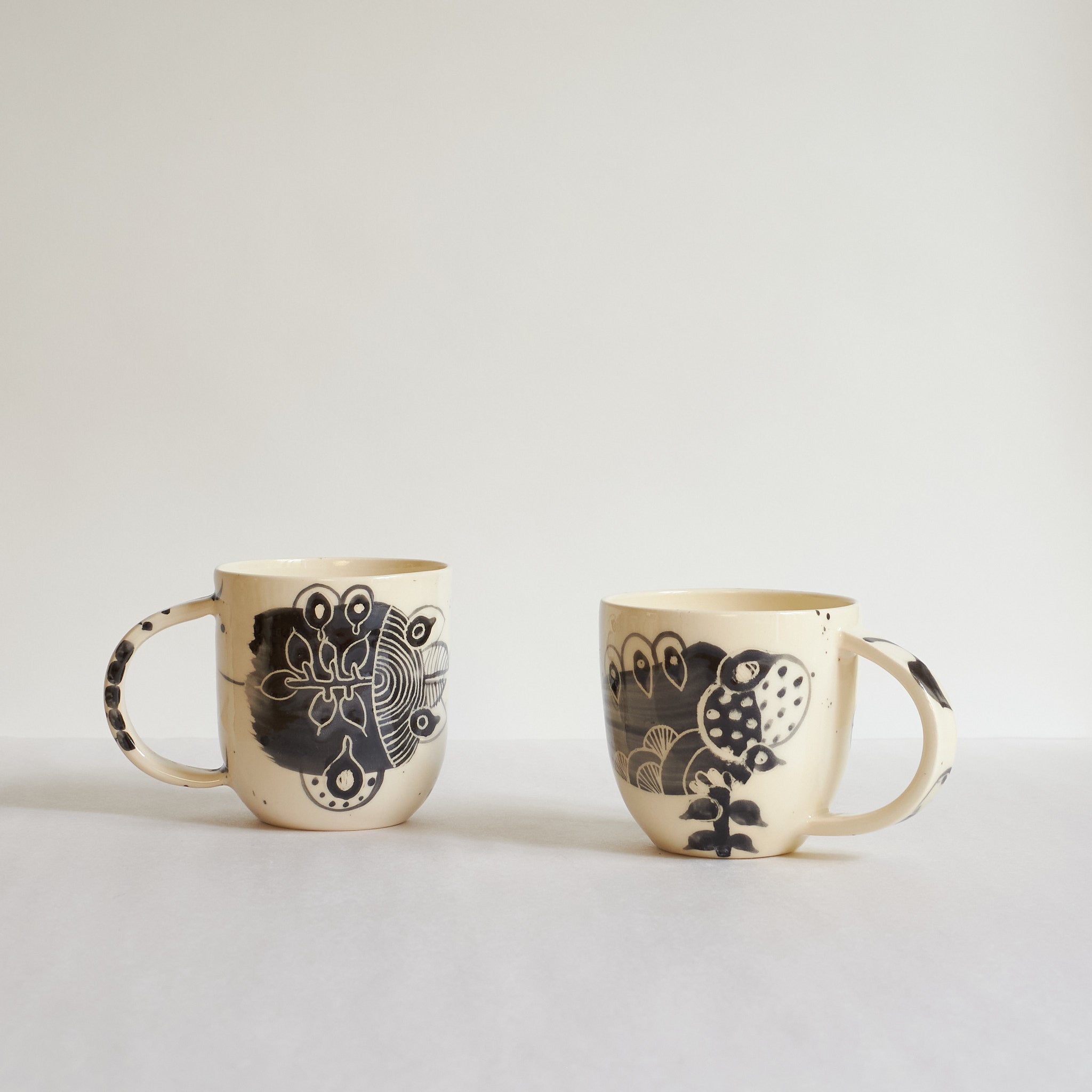 Two small black and white earthenware cups with unique carvings