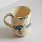 Tall white earthenware mug with blue carvings
