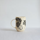 Tall white earthenware mug with black carvings