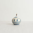 Earthenware lidded box with blue carvings and beaded pull on a light gray background