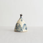 Decorative earthenware lidded box with blue carvings on a light gray background