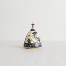 Earthenware lidded box with black carvings and beaded pull on a light gray background