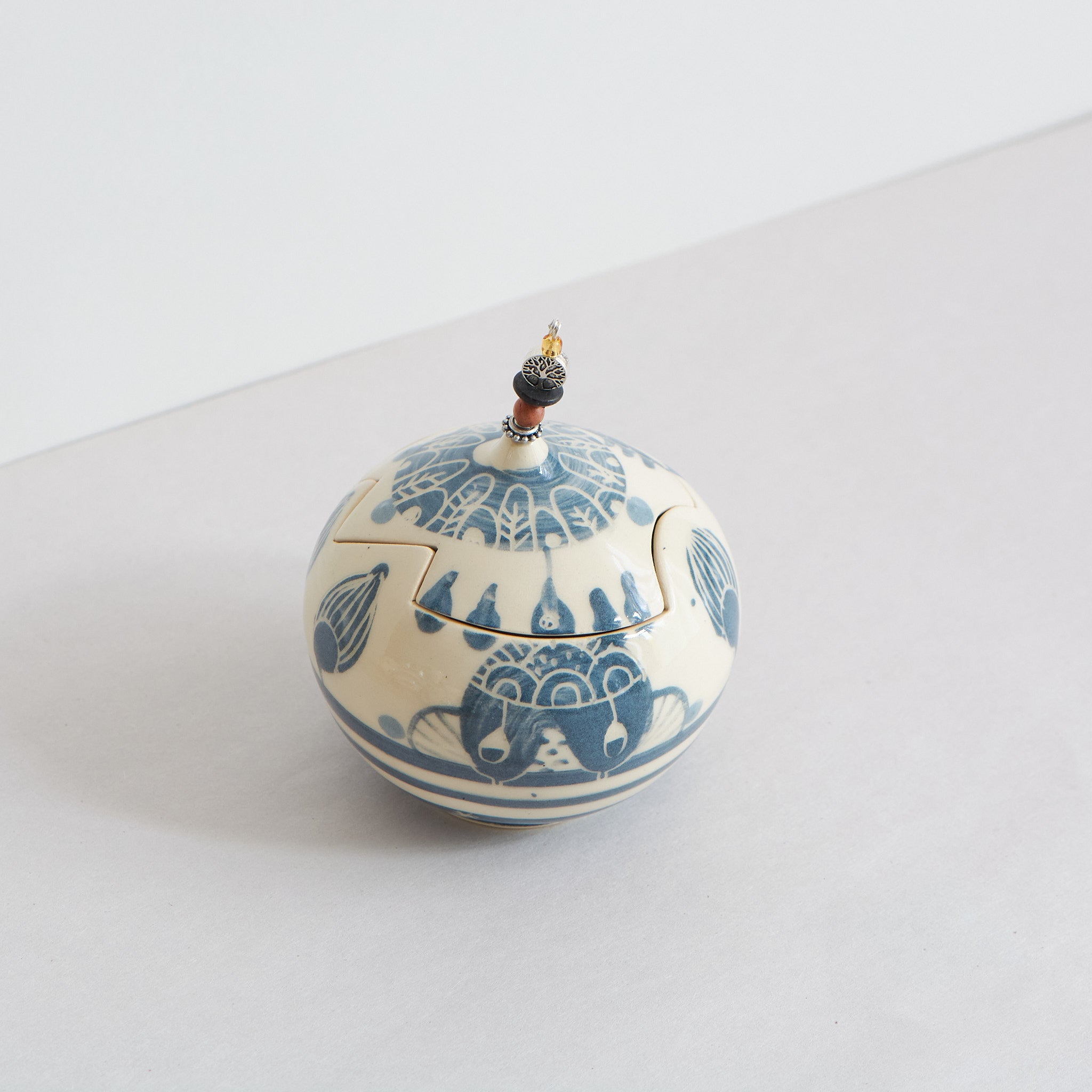 Ceramic lidded box with blue carvings on a light gray background