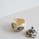 Ceramic box and lid with black and white patterns on a light gray background