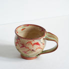 Handmade ceramic mug with Japanese maple tree leaf patterns on a white background