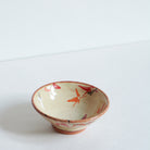 Small ceramic sake bowl with Japanese maple leaf design on a white background
