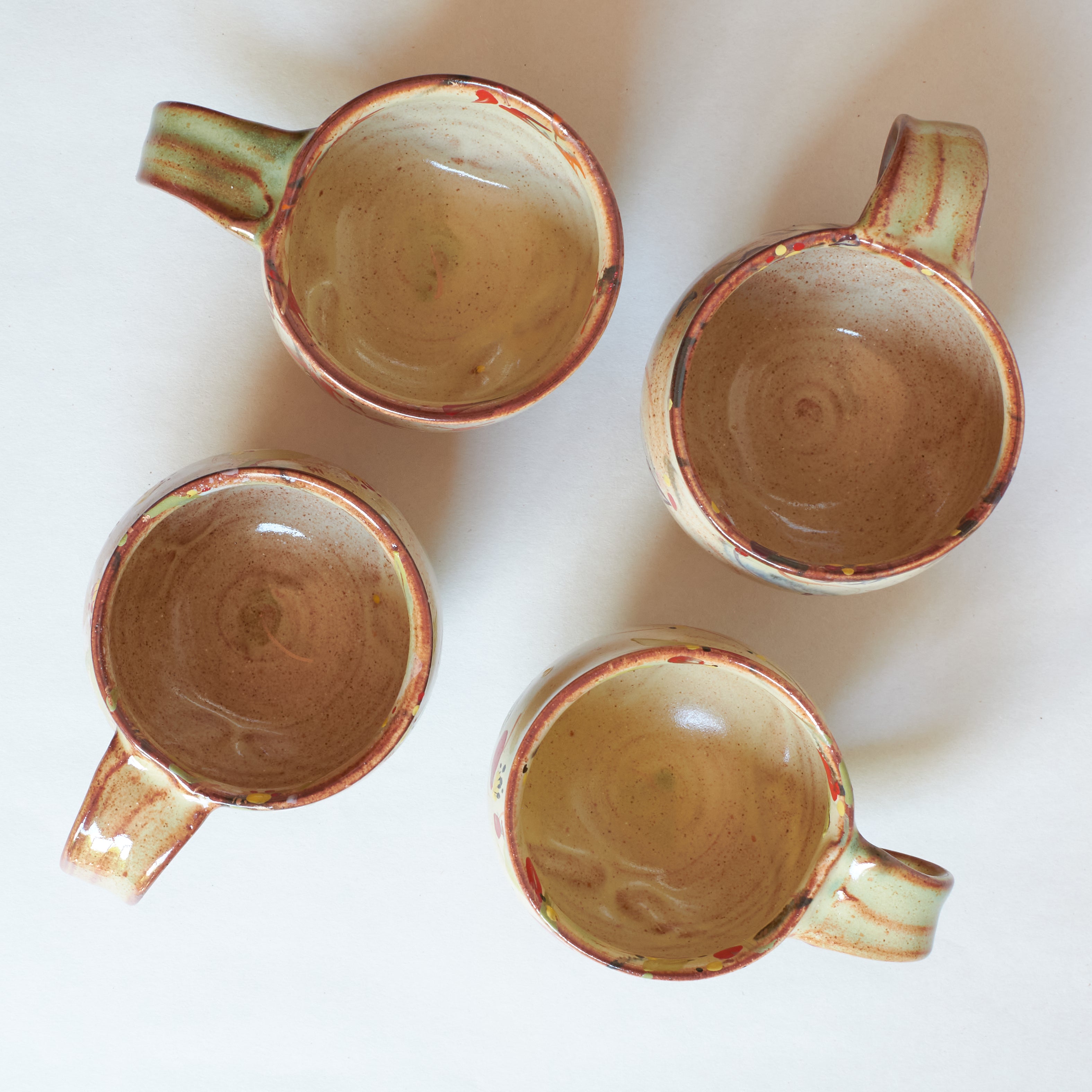 Inside of four ceramic mugs with a rustic finish on a white background