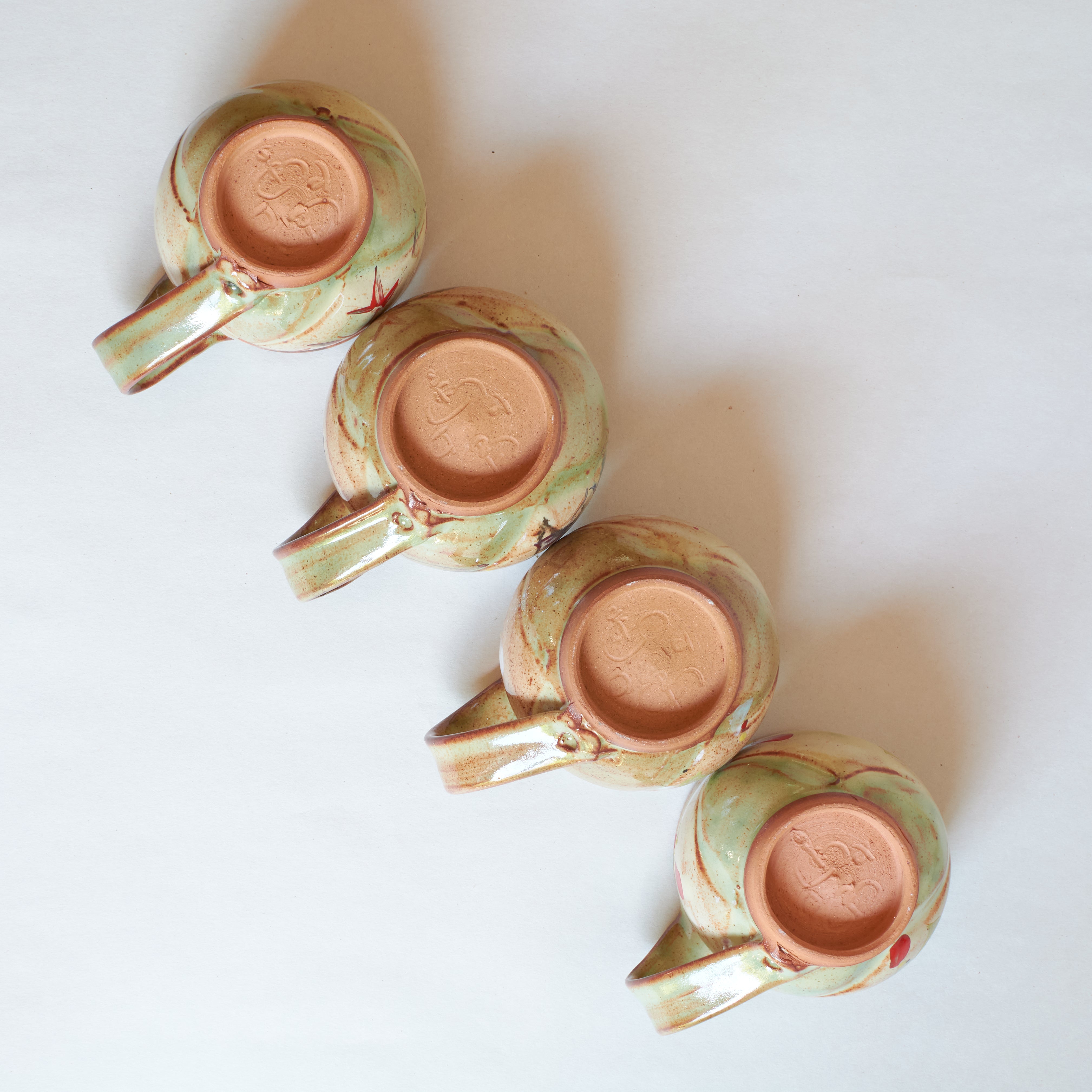 Bottom of four ceramic mugs with a floral pattern on a white background