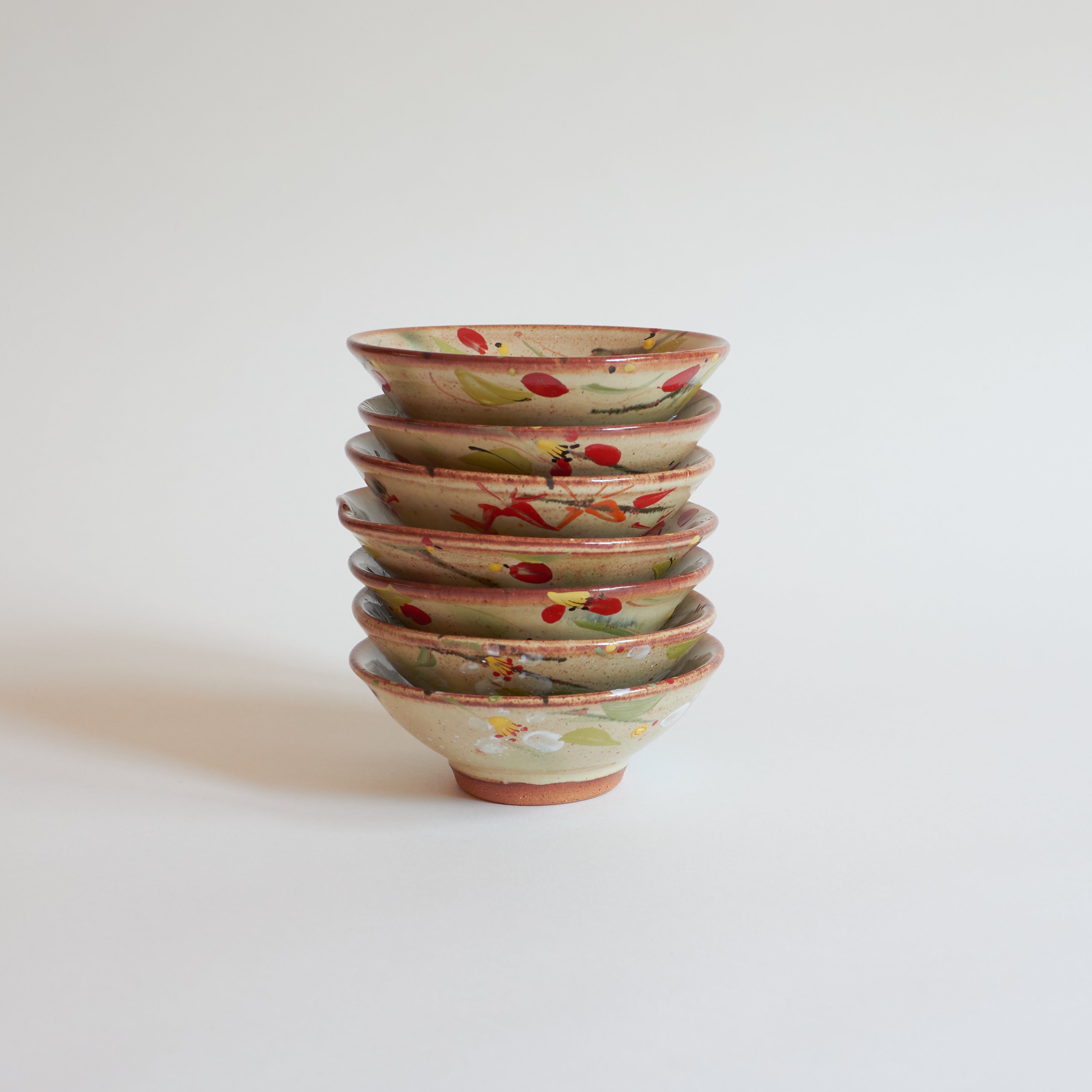 Stack of ceramic bowls with floral patterns on a light background