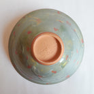 Bottom of ceramic bowl with red clay and floral design on a white background
