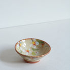 Small ceramic bowl with white cherry blossom floral design on a white background