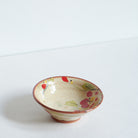 Small ceramic bowl with red camellia floral patterns on a white background