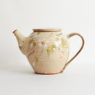 Side view of ceramic teapot with cherry blossom design on a light background