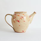Side view of ceramic teapot with japanese maple tree design on a light background